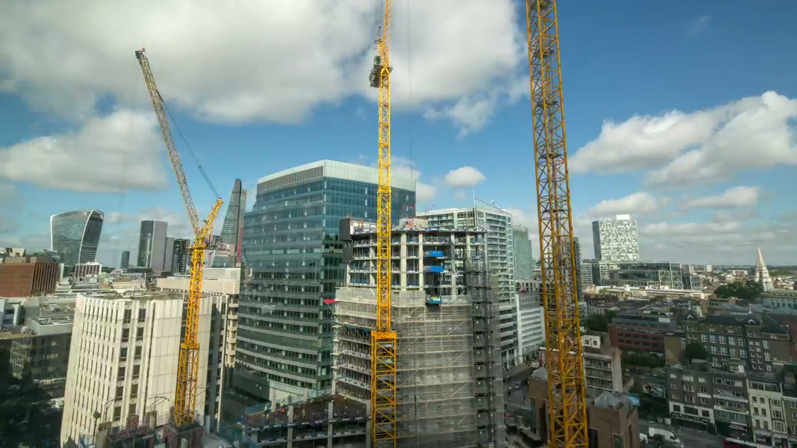 Aerial construction site with tower cranes over buildings under construction.