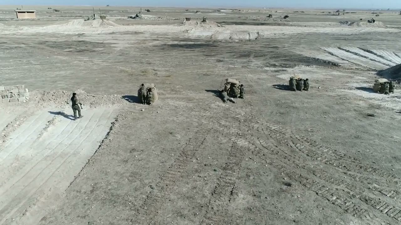Illustrative desert training-ground aerial frame with personnel, berms, and terrain context.