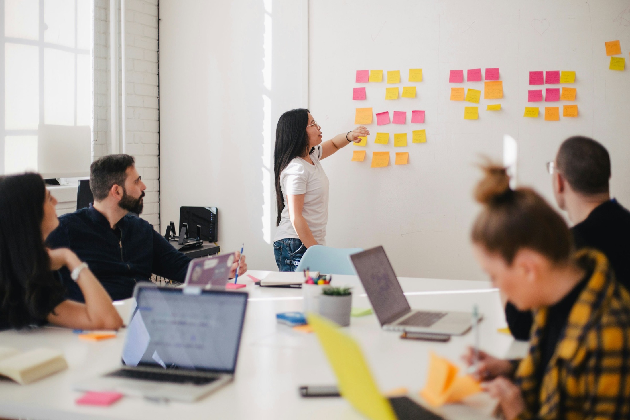Team facilitating a workshop session with sticky-note planning on the wall.