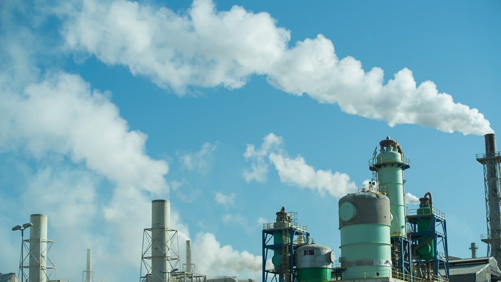 Industrial plant towers and steam outlets against an overcast sky.