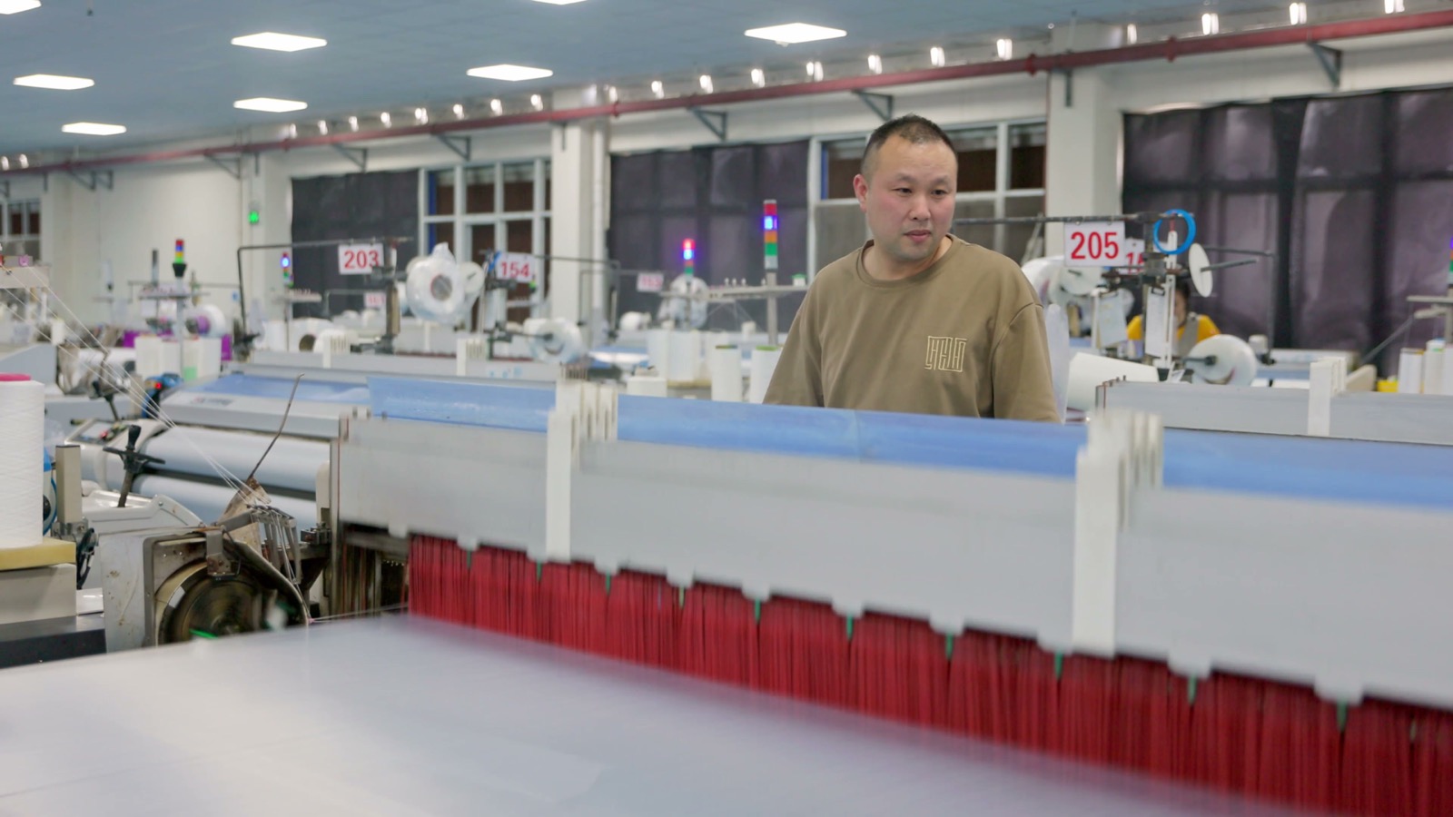 Operator standing among numbered production machines on a factory floor.